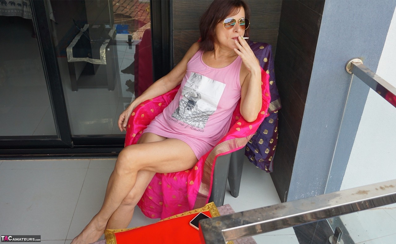 Older amateur Diana Ananta smokes while showing her pussy on a balcony