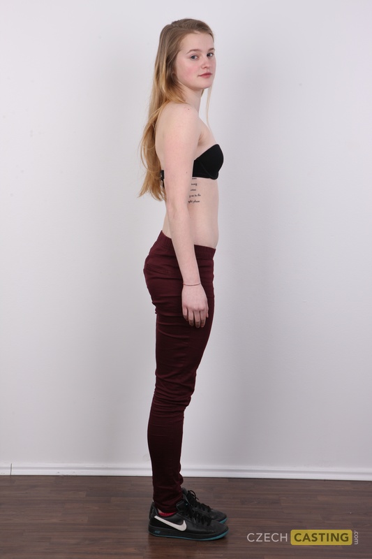Caucasian girl with long hair stands naked after stripping off her clothes
