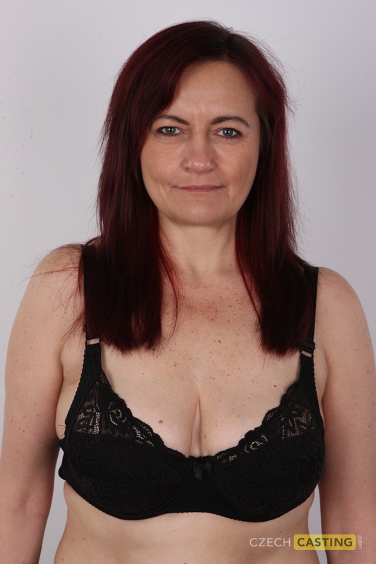 Mature woman with red hair stands straight while getting completely naked