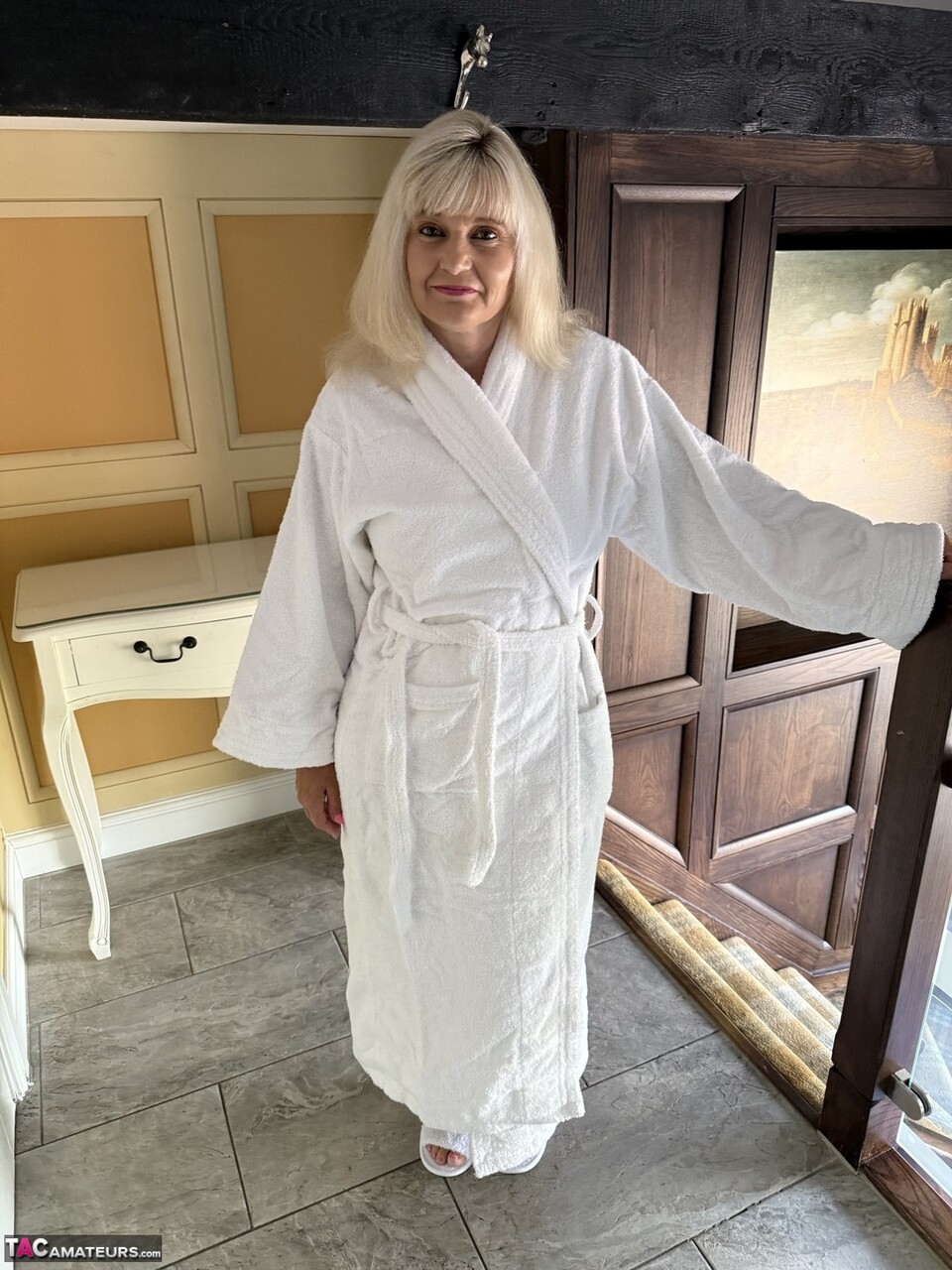 Mature blonde unveils her big natural tits before getting in a bathtub