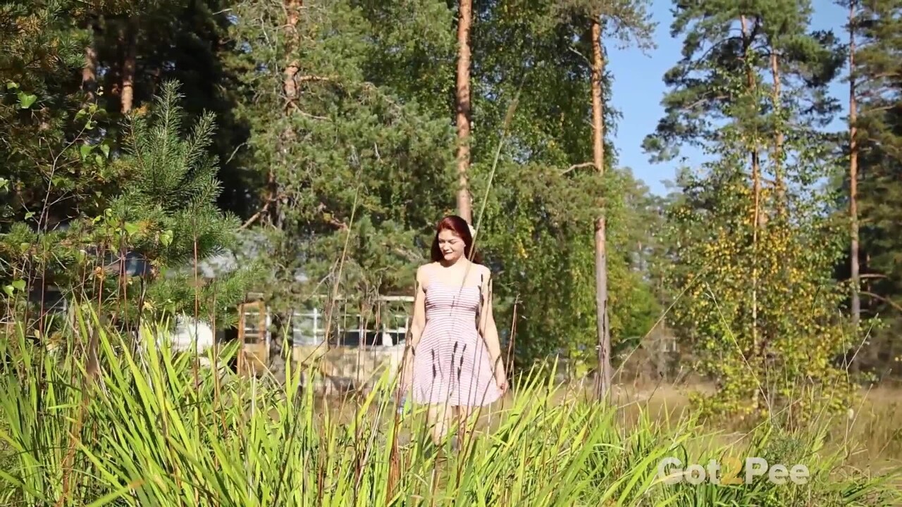 Redheaded girl Foxy Dream leans back in the grass to take an outdoor piss