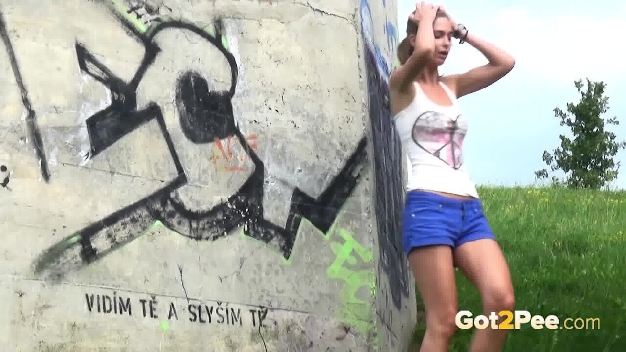 Pretty girl leans up against a concrete installation for a badly needed piss