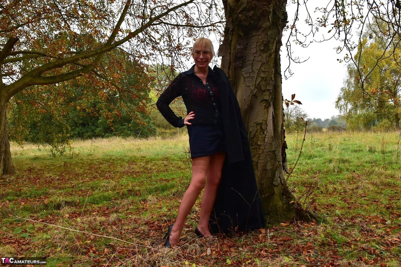 Mature lady Barby Slut gets naked in a field while wearing nylons