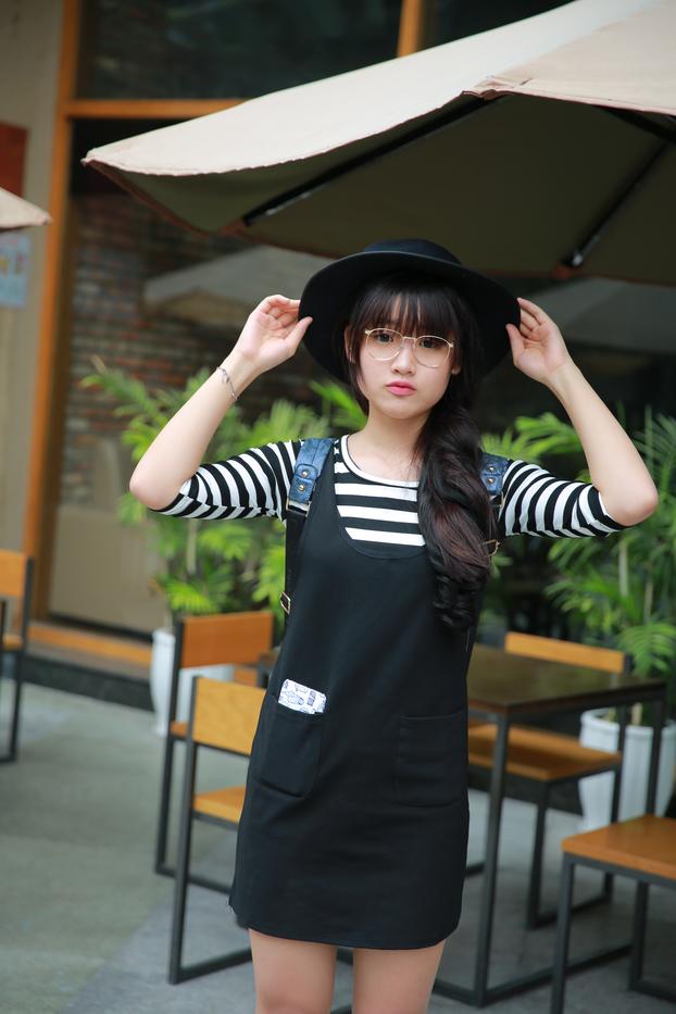 Short Asian model with a hat posing in her lovely outfit in public