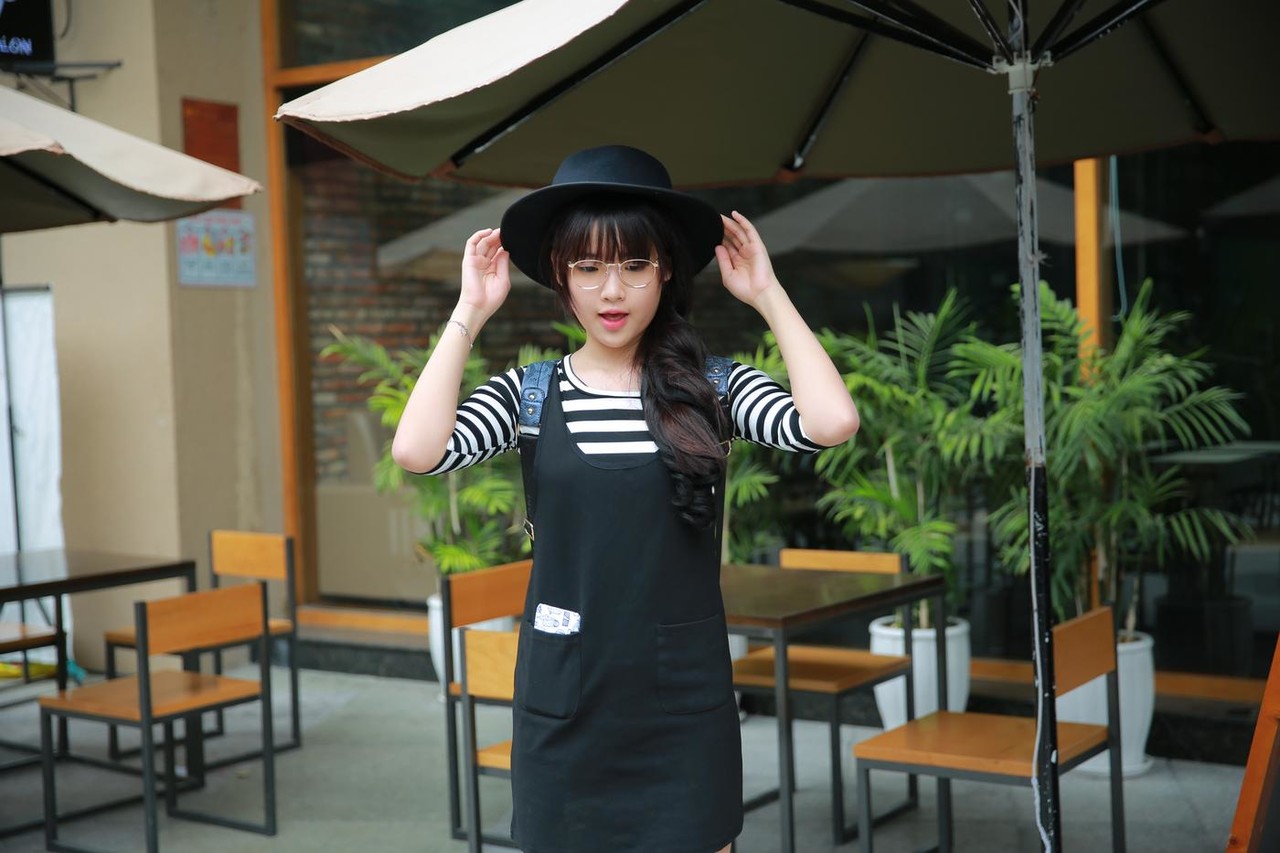Short Asian model with a hat posing in her lovely outfit in public