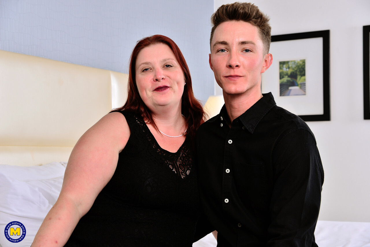 Older redhead has sexual intercourse with her younger lover upon a bed