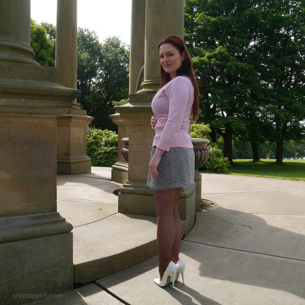 Redhead model showcases her hot legs in a short skirt and high heels
