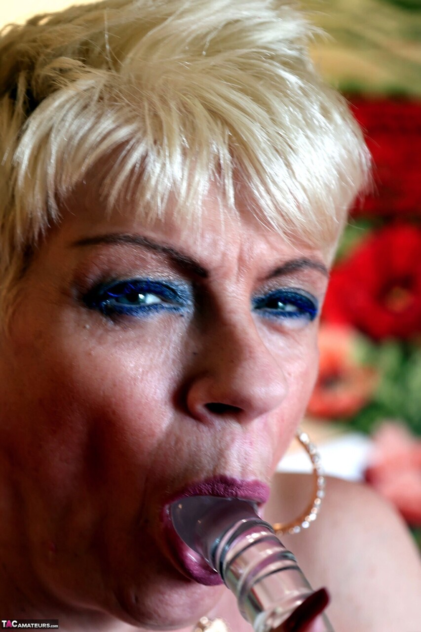 Older blonde is restrained in a slave collar and cuffs before masturbating