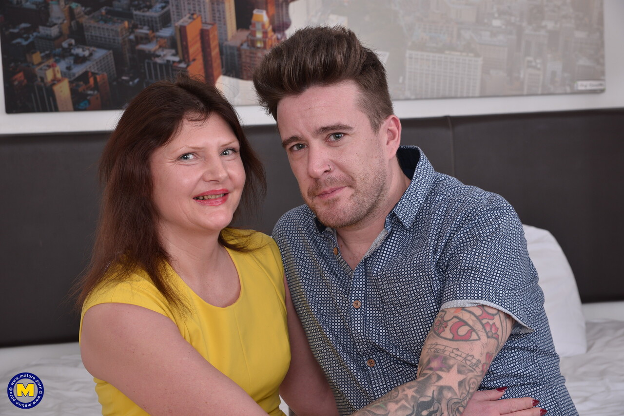 Mature woman has sexual intercourse with a tattooed boy on a bed