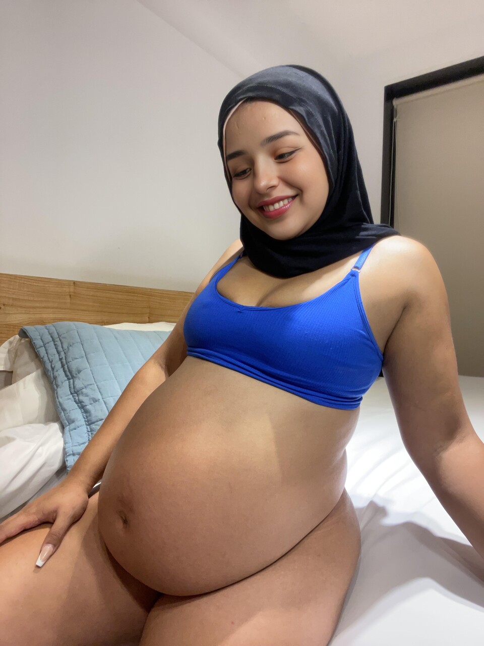 Solo model from the Middle East shows her huge belly while wearing a black niqab