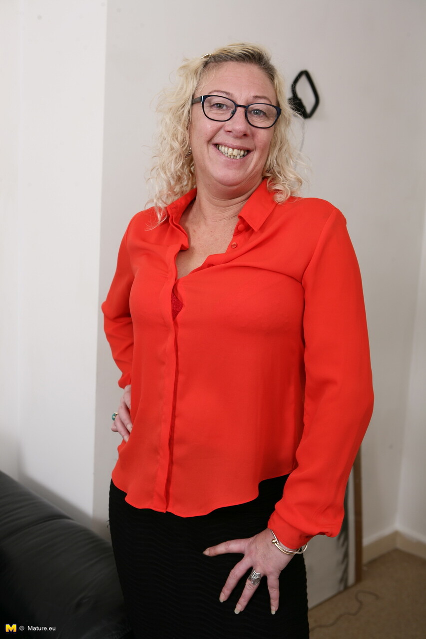 Curly haired granny in black stockings takes off her glasses while modeling