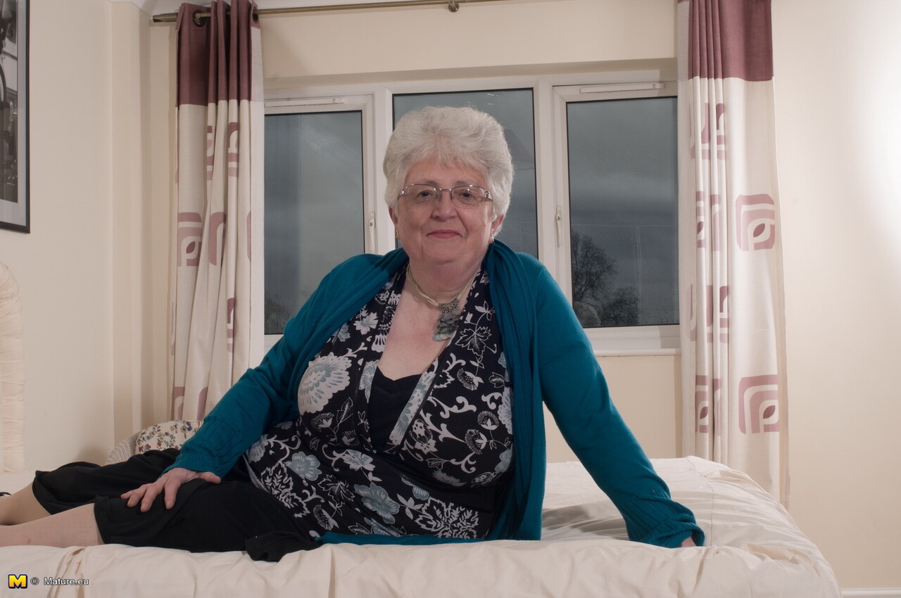 Old woman takes off her glasses and clothing to go topless in her underwear