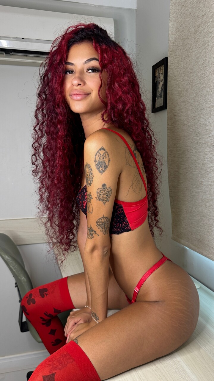 Tattooed redhead models lingerie and a red dress during solo action