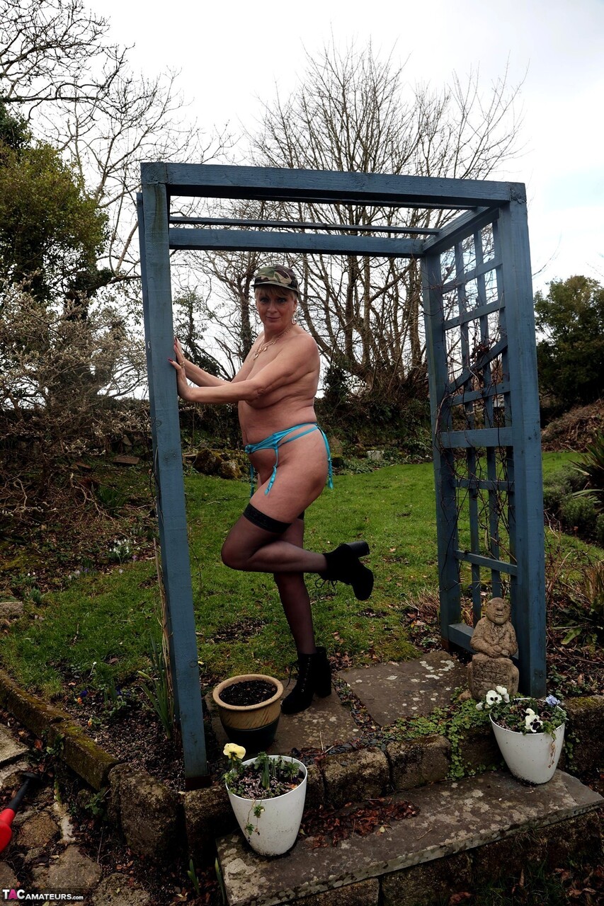 Older amateur shows her big tits on a garden patio in black stockings