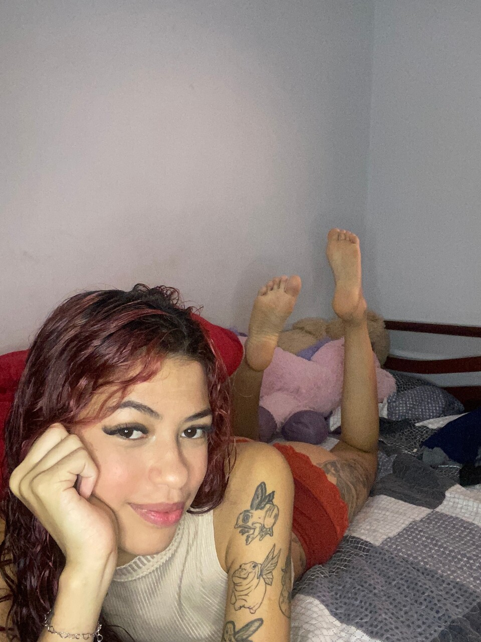 Cute girl with red hair shows her bare feet on top of her bed