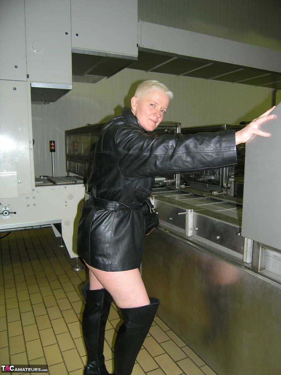 Blonde amateur Tiffany Pearl takes off her leather raincoat in a kitchen