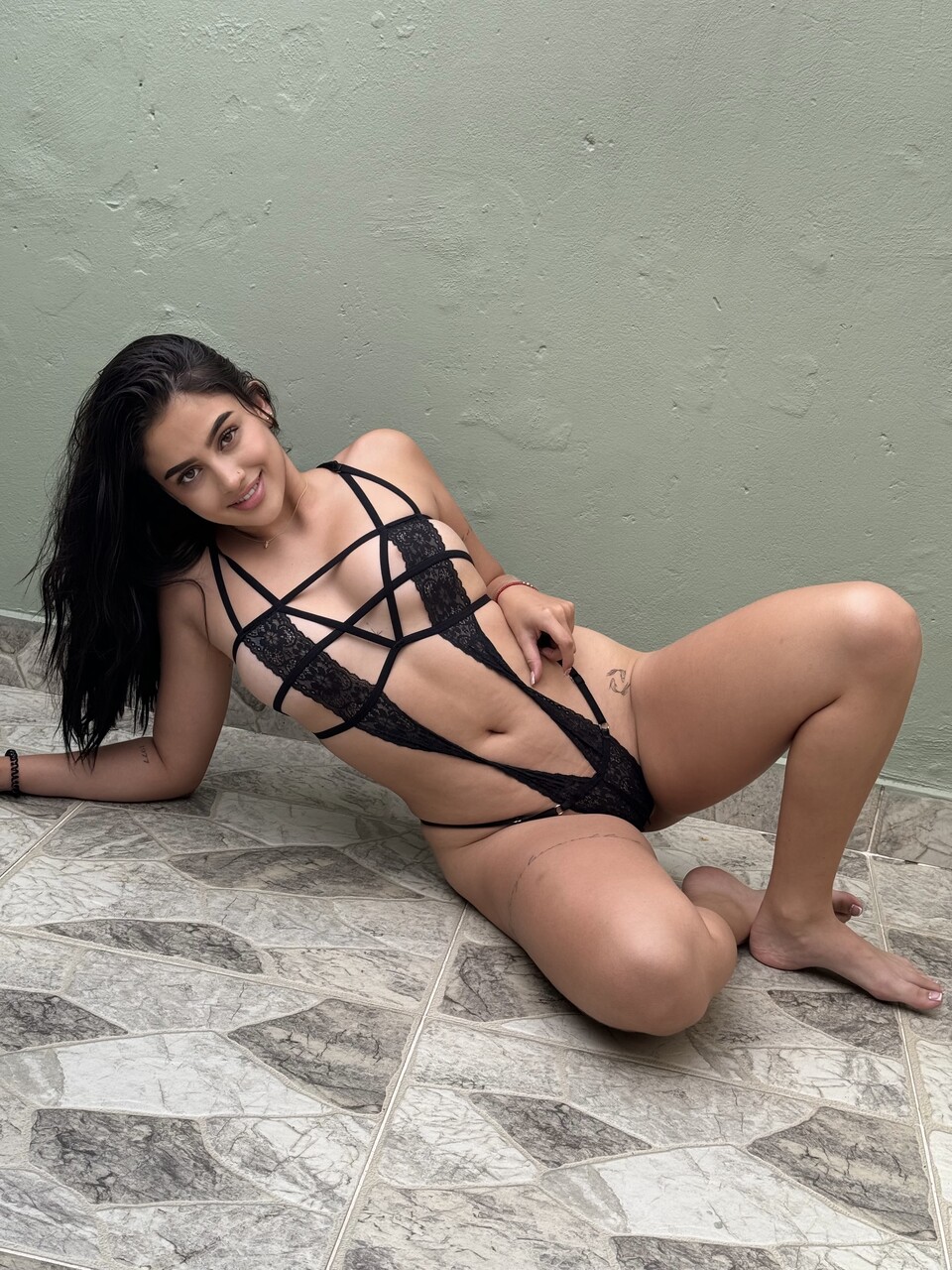 Solo model with long hair poses on a patio in revealing lingerie