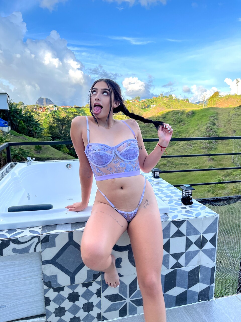Brunette teen shows her teeth in revealing lingerie on a balcony