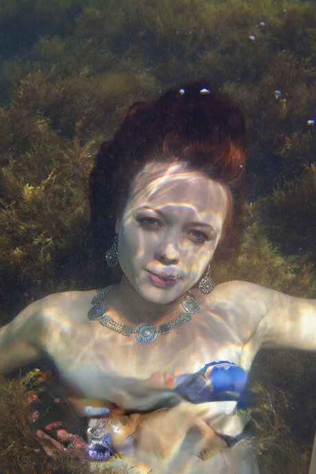 Redheaded teen goes topless underwater before posing naked on an air mattress