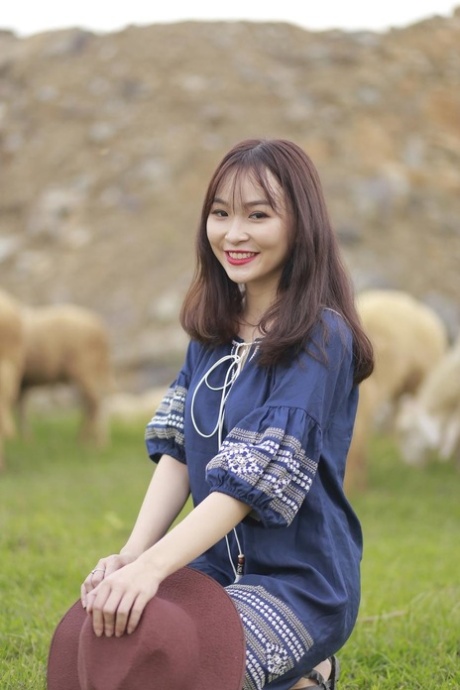 Hot Asian countryside girl poses in her lovely outfit among a sheep flock