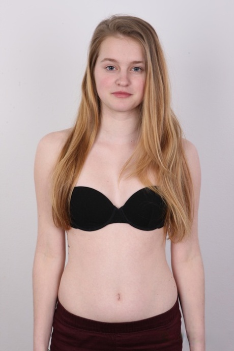 Caucasian girl with long hair stands naked after stripping off her clothes