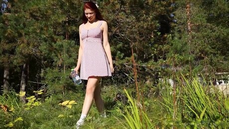 Redheaded girl Foxy Dream leans back in the grass to take an outdoor piss