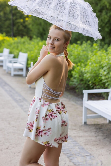 Nice teen Avrora holds a parasol before getting naked on an outdoor bench