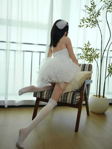 Dark-haired doll with big blue eyes displays her vagina in a white dress
