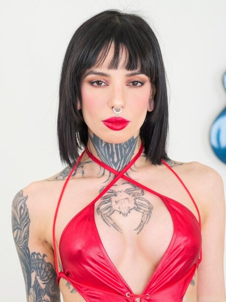 Tattooed brunette with red lips sucks on a cock after removing her dress