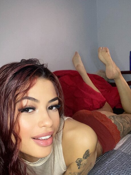 Cute girl with red hair shows her bare feet on top of her bed