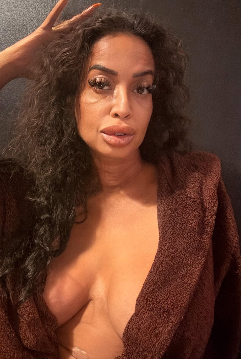 Solo girl with perky tits and curly hair holds her chin to tease with her tongue